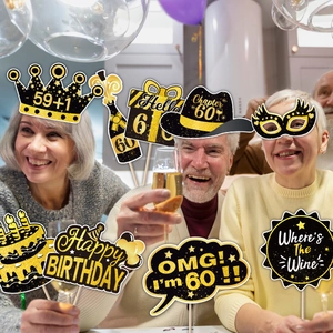 Cheerful seniors using 60th birthday photo booth props in black and gold theme