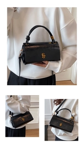 Detail of black glossy leather handbag featuring gold clasp and knotted top handle design