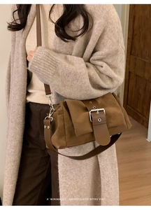 Détail d'un sac bandoulière vintage en daim marron avec grande boucle argentée et sangle