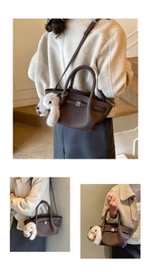 Detail der dunkelbraunen Tasche aus Narbenleder mit Silberschnalle und Plüsch-Anhänger