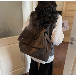 Detail view of large dark brown frosted backpack with metal buckle on model back