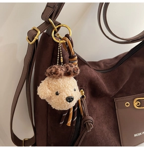 Gros plan sur un bijou de sac chien en peluche avec nœud léopard et corde tressée