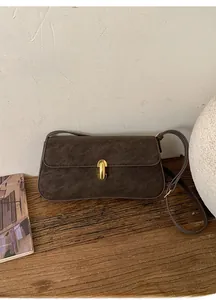 Gros plan détaillé du sac porté épaule en daim marron foncé avec boucle dorée mate