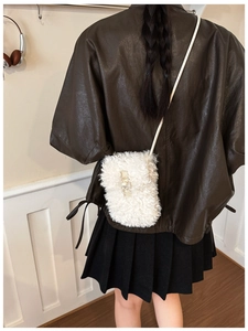 Detail of white faux fur bucket bag worn by model showing plush texture and strap