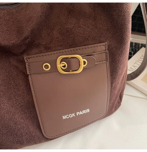 Détail d'un sac en daim marron foncé avec poche en cuir et boucle dorée