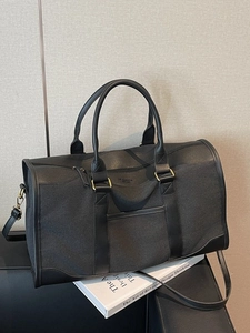 Black canvas travel duffel bag with leather trim and adjustable shoulder strap