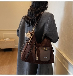 Détail du sac cabas en daim marron foncé avec logo MCGK PARIS et breloque chien en peluche
