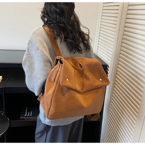 Close-up of caramel suede backpack with a large fold-over flap and silver metal studs