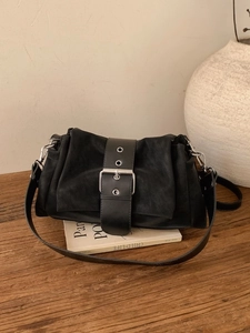 Sac à main rétro en cuir noir avec boucle vintage et plis sur un bureau en bois
