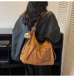 Détail du sac cabas en daim marron avec logo MCGK PARIS, boucles dorées et breloque chien