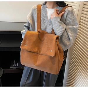 Detail of camel suede backpack featuring a magnetic flap closure and wide shoulder straps