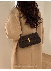 Détail du sac à bandoulière en similicuir marron foncé avec fermoir doré cylindrique