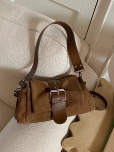 Sac sous le bras vintage en daim marron avec grande boucle argentée sur canapé