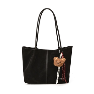 Minimalist black faux leather tote bag with white contrast stitching and plush charm
