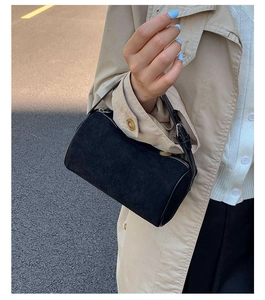 Detail of a black suede cylinder bag with silver zipper and leather strap for women