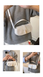 Detail of white patent leather shoulder bag with polished gold clasp and long strap