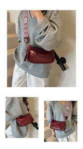 Detail of burgundy glossy leather crossbody bag with patterned wide fabric strap
