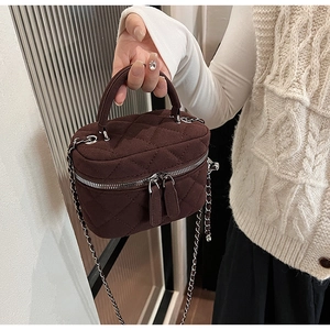 Detail view of burgundy quilted suede mini crossbody bag with gold chain and handle