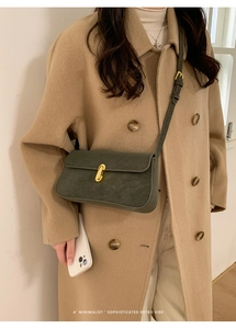Détail d'un sac à bandoulière en PU vert foncé rétro avec fermoir doré sur un manteau