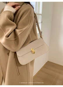 Gros plan d'un sac sous le bras en cuir PU crème avec fermoir doré sur un manteau beige