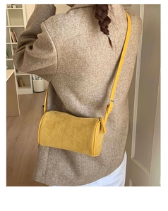 Model wearing a yellow suede cylinder crossbody bag with a beige tweed blazer and white pants