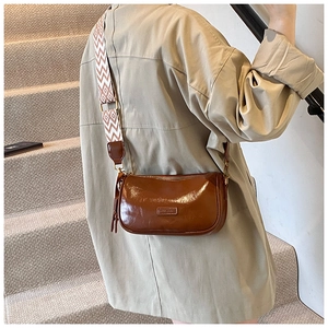 Detail of dark brown vintage Boston bag with patterned strap on a staircase