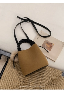Detail of warm brown textured bucket bag with woven handle and plush charm accessory