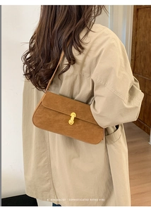 Gros plan d'un sac porté épaule en daim marron minimaliste avec fermoir doré sur un modèle
