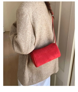 Model showing a red cylindrical crossbody bag made of premium matte suede leather