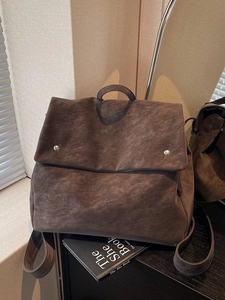 Minimalist dark brown suede backpack featuring vintage textures and metal rivet details