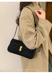 Détail d'un sac sous le bras en daim noir avec boucle en métal doré au style minimaliste
