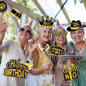 Women using 80th birthday photo booth props with black and gold glitter crown and glasses
