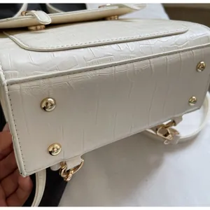 Detail of white crocodile embossed leather bag base with protective gold metal rivets