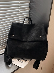 Minimalist black matte leather backpack with silver studs shown in artistic lighting