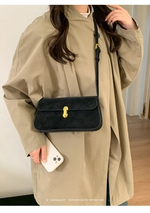 Sac à bandoulière chic en suédine noire avec boucle dorée élégante porté par un mannequin