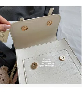 Detail of powerful magnetic buckle closure on white crocodile embossed leather bag