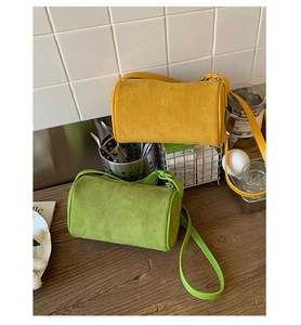 Detail of yellow and green cylindrical crossbody bags in soft suede with leather trim
