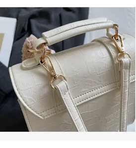 Detailed close-up of white crocodile pattern handbag with luxury gold hardware accents