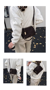 Detailed macro view of dark brown suede crossbody bag with elegant gold metal buckle hardware
