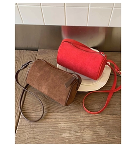 Close-up of suede cylinder crossbody bags with leather trim and metal zippers
