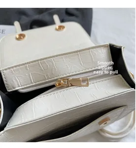 Detailed close-up showing the smooth golden metal zipper of the white crocodile handbag