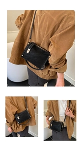 Detail of vintage black crossbody bag showing gold twist lock and matte leather texture