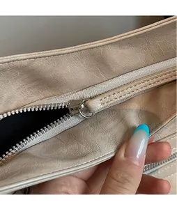 Detail of beige wrinkled leather tote featuring long zipper pull and secure closure