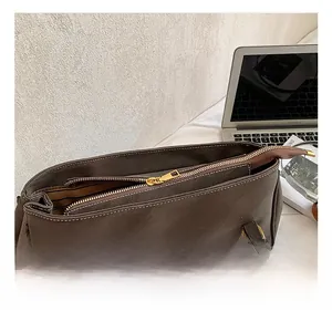 Detail of dark brown tote bag featuring golden hardware and white contrast stitching