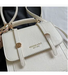 Detailed view of white crocodile texture leather with gold buckle and brand logo