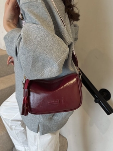 Deep red crescent shoulder bag with branded embossing and woven strap on model