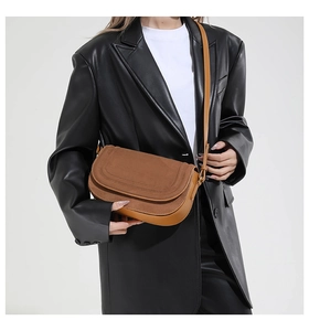 Detailed view of brown saddle bag with suede flap and smooth leather worn by a model