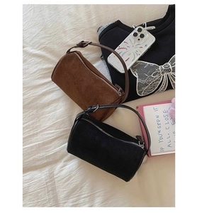 Detail of suede cylinder handbags in dark brown and black with zipper and slim handles