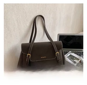 Detail showing the brown suede texture, flap closure and gold buckle of the shoulder bag