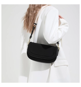 Detail of black saddle bag with a stylish black and white woven adjustable shoulder strap